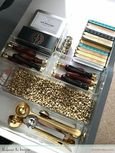 an organized drawer filled with various items and gold accents, including pens, pencils