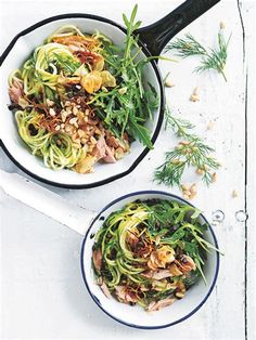 two bowls filled with food on top of a white table