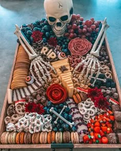 a tray filled with lots of different types of food on top of a table next to a skull