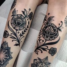 two legs with tattoos on them sitting on a white blanket and one has a flower