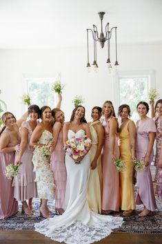 a group of women standing next to each other in front of a chandelier