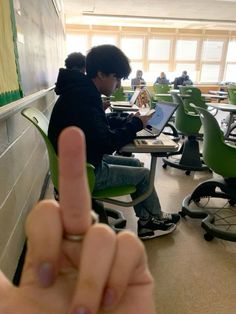 a person sitting at a desk with a laptop in front of them making the middle finger sign