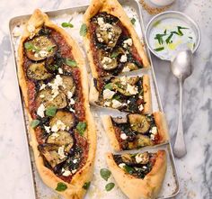 two rectangular pizzas with mushrooms, feta cheese and herbs on a baking sheet