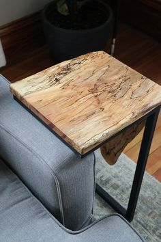 a small wooden table sitting on top of a gray couch next to a potted plant