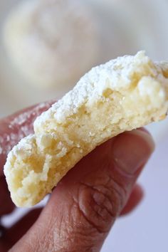 a hand holding a half eaten doughnut with powdered sugar on the top and bottom