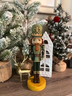 a nutcracker figurine sitting on top of a table next to christmas trees