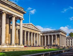 an old building with columns and grass in the foreground, on a sunny day