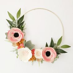 a wreath with flowers and greenery hanging on the wall