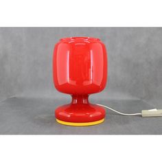 a red table lamp with a white cord plugged in to it's base