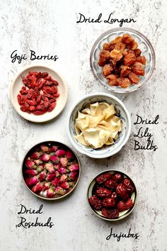 four bowls filled with different types of dried fruits and vegetables next to each other on a white surface