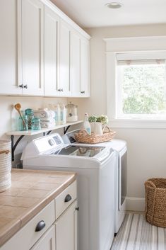 a washer and dryer sitting in a kitchen next to a window with white cabinets