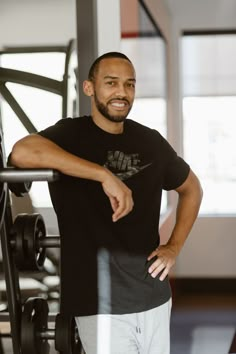 a man standing next to a barbell in a gym with one hand on his hip