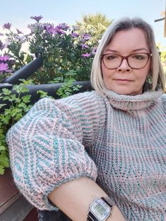 a woman wearing glasses and a sweater is sitting on a bench with her arm wrapped around her neck