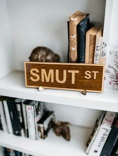 a wooden sign sitting on top of a white book shelf next to bookshelves