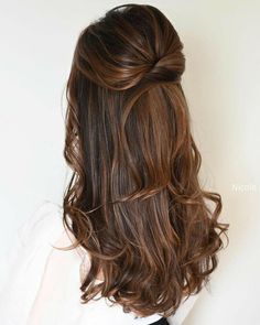 the back of a woman's head with long, wavy hair in half - up style