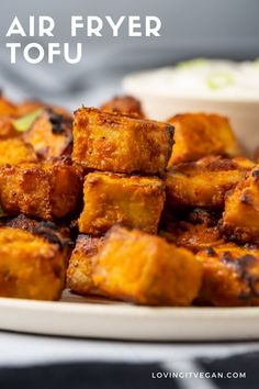 fried tofu cubes on a white plate with dipping sauce in the background text reads air fryer tofu