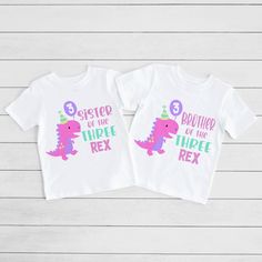 two white shirts with pink and purple dinosaurs on them, one says sister and the other says