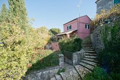 an outdoor area with steps leading up to a pink building and trees in the background