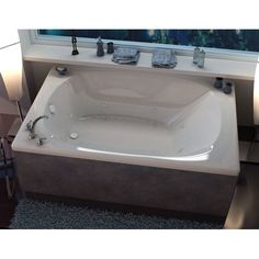 a bath tub sitting next to a window on top of a bathroom counter with candles