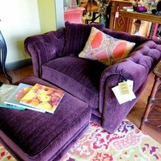 a purple chair and footstool with a book on it in a living room