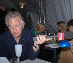 an older man holding a remote control in his right hand while sitting at a table