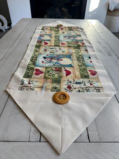 a white table with a wooden button on it and a quilted placemat in front of a fireplace