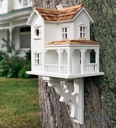 a white bird house on the side of a tree