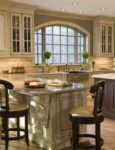 a large kitchen with an island in the middle and two stools at the end