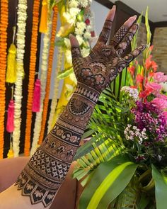 a woman's hand with henna on it and flowers in front of her