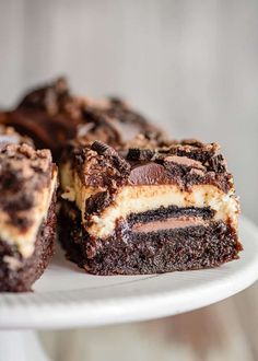 a white plate topped with brownies covered in oreo and cheesecake toppings