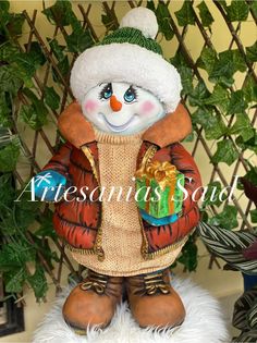 a snowman with a gift in his hands on top of a white fur rug