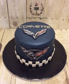 a cake with the name corvette on it sitting on top of a wooden table next to a plaque