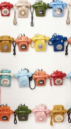 there are many telephones hanging on the wall with keys attached to them, all different colors