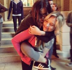 two women hugging each other in front of some people on the steps and one woman is holding her