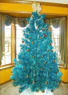 a blue christmas tree in front of a window