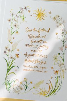 a wedding card with flowers and the words save the date written in gold on it