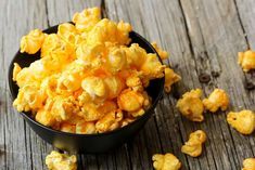 a black bowl filled with popcorn on top of a wooden table