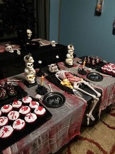 a table topped with cupcakes covered in frosting next to skulls and skeletons