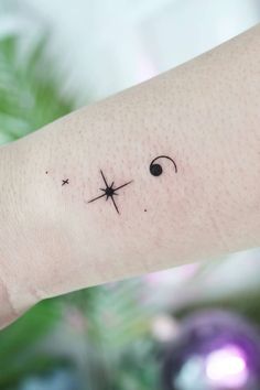 a person's arm with a small cross tattoo on it