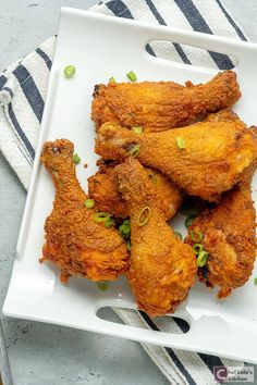 fried chicken wings on a white plate with green onion sprinkles and seasoning