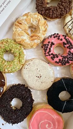 a box filled with lots of different flavored donuts on top of a table