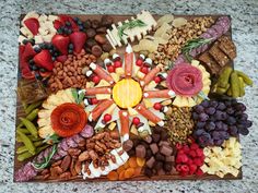 a wooden tray filled with lots of different types of fruit and snacks on top of a table