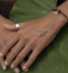 a woman's hand with a small tattoo on the left wrist and a tiny flower on the right wrist