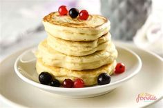 a stack of pancakes topped with berries and syrup