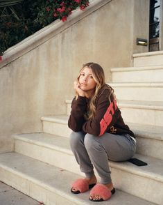 a woman is sitting on the steps with her hand under her chin