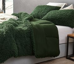 a bed with green blankets and pillows on it