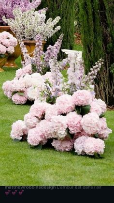 pink and white flowers line the grass in front of potted plants on either side