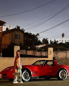 a man standing next to a red sports car