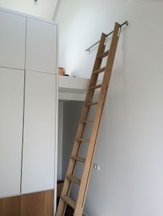 a ladder leaning up against the wall in a room with white walls and cupboards