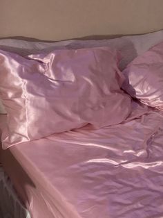 an unmade bed with pink sheets and pillows